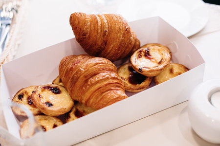 Bakery products, baked sweet croissants, cakes in packaging cardboard box on table for breakfast. Hotel cateringの写真素材