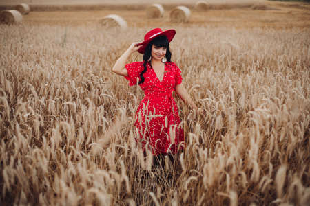 Beautiful woman in red dress and hat in field.の写真素材
