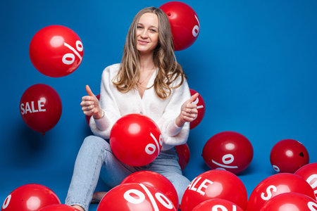 beautiful female model poses for the camera with a lot of red air baloons rejoices