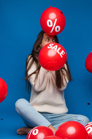 Astonished woman with air balloons flying around.