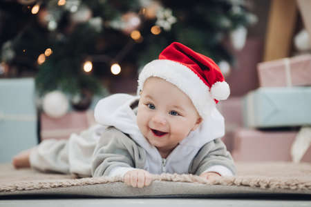 Adorable baby in red Santa hat on floor.の写真素材
