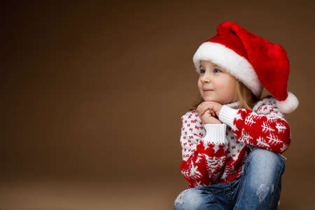 Little girl having a seat in a sweater with Christmas treesの写真素材
