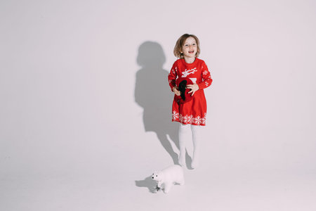 little girl in red dress holds a hat and laughs
