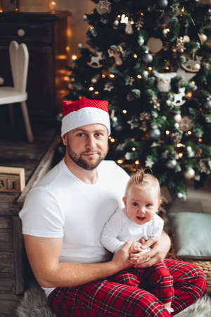 Smiling man in Santa hat sitting with his kid on the floor at homeの写真素材
