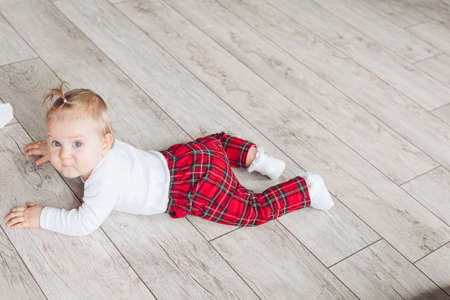 Little cute baby in pretty sleepwear lies on the white floorの写真素材