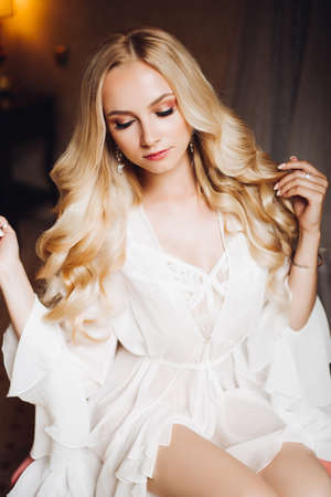 Beautiful blondie bride in bedroom, dreaming with closed eyes.の写真素材