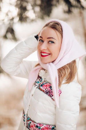 Beautiful Russian woman in a headscarf, portrait. A lovely woman smiles and looks at the camera in winter.の写真素材