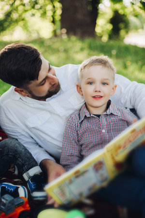 Handsome father throwing baby boy against summer park.の写真素材
