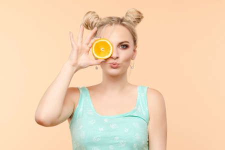 A beautiful sweet charming fresh bright woman with a cool hairstyle holds 2 orange slices in her hands, summer, joy, brightness copy space for advertisementの写真素材