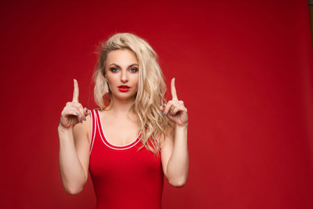 Beautiful blonde in a red swimsuit with bright makeup and red lipsの写真素材