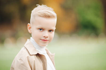 Stylish boy in a coat in autumn in the park, autumn forestの写真素材