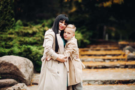 Mom and son are on good terms, walking in the park, chatting. Stylish family, family lookの写真素材