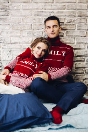 Couple wearing in red sweaters embracing and celebrating xmas.の写真素材