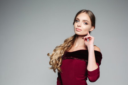 Studio portrait of attractive blond woman with long thick hair tied in ponytail and professional...