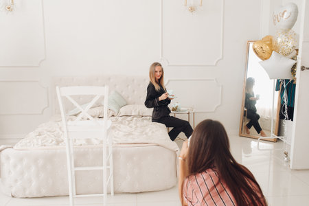 Beautiful blonde in pajamas with cup of coffee on bed.の写真素材