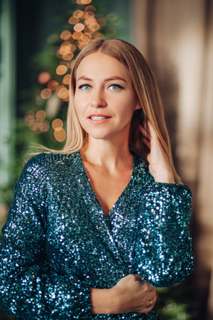 A beautiful woman in a stylish dress near the Christmas tree is smilingの写真素材