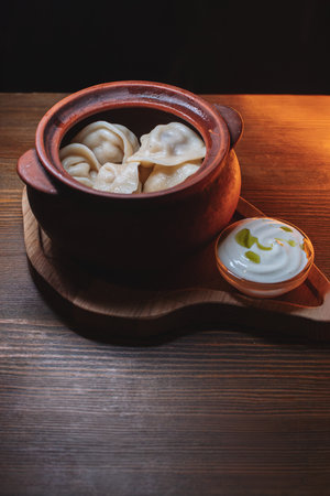 Hot, juicy dumplings snuggled in a pot. Next to it is a spoonful of sour cream to make this dish even tastier.の写真素材