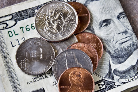 Coins laying on a five dollar bill ( quarter, nickel, dime, penny )