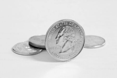 Quarter standing on edge with coins in background on whiteの写真素材