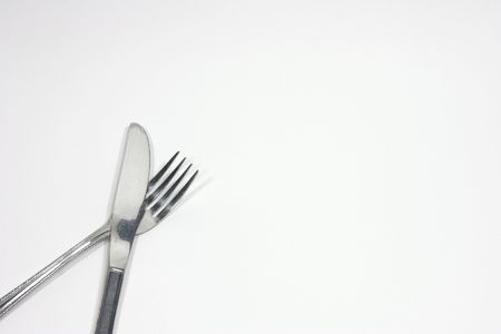 Dinner serving fork and knife in corner on white backgroundの写真素材