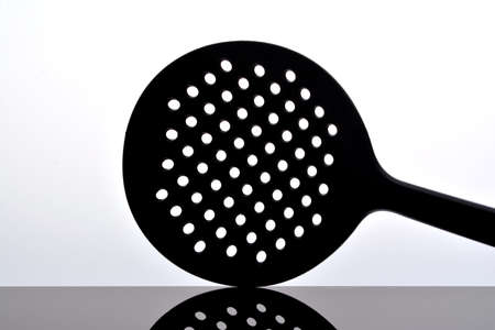 Skimmer, kitchen tools isolated on white on glossy black surface with reflectionの写真素材