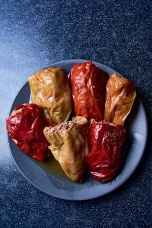 Sweet peppers stuffed with minced meat on a wooden blue background. View from above.