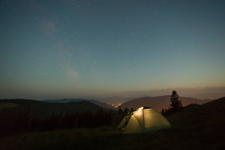 A summer night a tent in the mountains stands under the stars.の写真素材