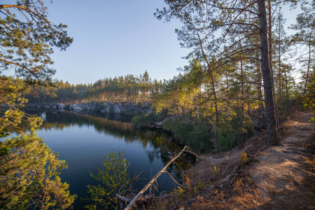 Trees on the shore of a beautiful quarry with clear water. Tall stone. Ukraine.の写真素材