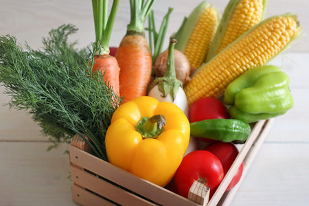 Useful vegetable set for a vegetarian in a box on wooden background top view. Corn, pepper, carrot,...