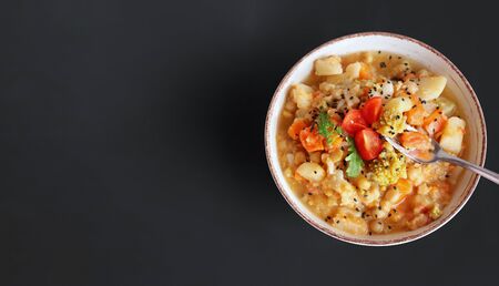 Vegetable vegan stew in a plate on a dark background top view with place for text. Healthy vegetarian homemade food consists of cabbage, beans, carrots, tomato and flax seeds.の写真素材