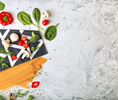 Top view of raw spaghetti on light background. Italian food ingredients. Pasta, tomatoes and spices.