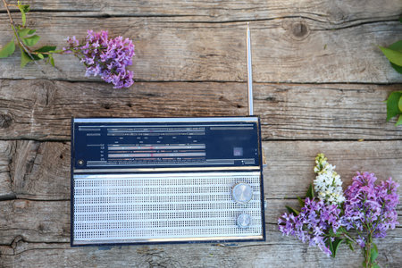 Vintage retro radio on a wooden board. Receiver and place for text. The concept of musical trends, music, old tracks. Lilacs in an old vase.の写真素材