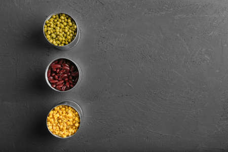 canned beans, peas and corn in a jar on a dark background top view. Three cans of canned legumes on a structural background from aboveの写真素材