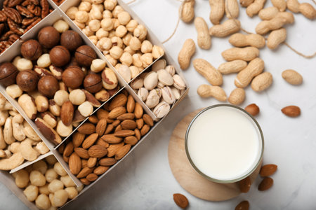 Assorted nuts in a wooden box (from top left: walnut, brazil nut, pecan, pistachios, almond, macadamia, peanut, cashew, hazelnut). Nut's milk. Healthy food, nuts as part of the dietの写真素材