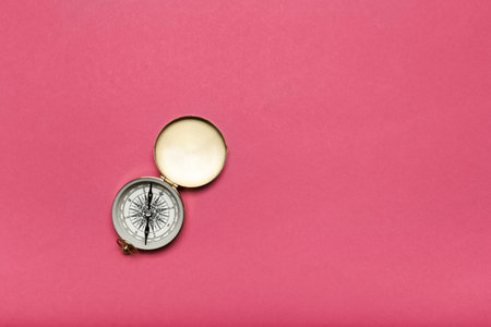 Old open shabby compass on a pink background. Sea and land guide top viewの写真素材