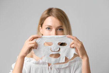 The girl puts on a cosmetic mask to cleanse her face. Morning cosmetic facial mask. Facial cleansing procedure in a beauty salonの写真素材