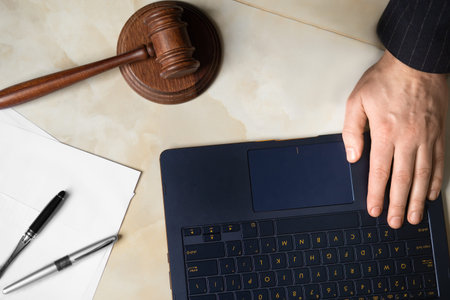 Judge's workplace top view. Judicial gavel, laptop, documents, male hands. Judge at work.