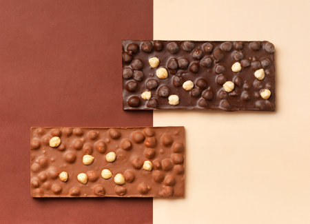 Handmade black and milk chocolate with hazelnuts on a brown and beige background top view. chocolate background.の写真素材