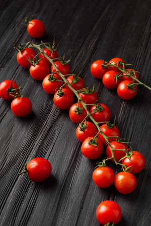 Fresh organic ?herry tomatoes on a branch on a dark wooden background. Health food. Veganism.の写真素材