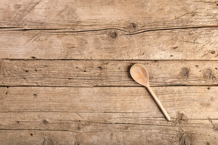 Wooden kitchen spoon on an aged wooden background top view with space for text.の写真素材