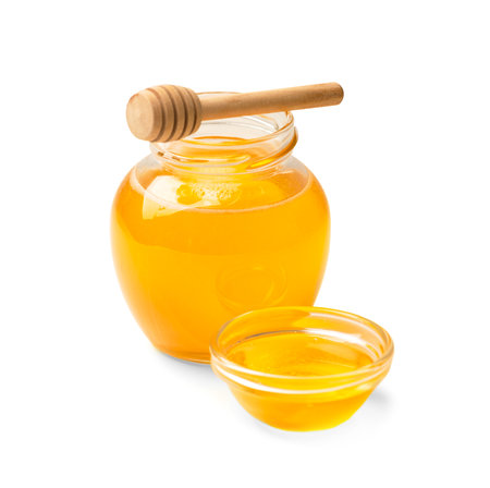 Organic honey in a glass jar and a transparent bowl, wooden dipper on a white background. Spoon for honey and fresh honey in an open jars on isolation close-up. health products.の写真素材