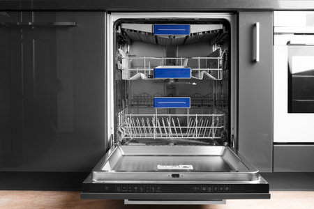 Modern built-in stainless steel dishwasher with open door in the kitchen front view. Household kitchen appliances. Dishwashing equipment.の写真素材