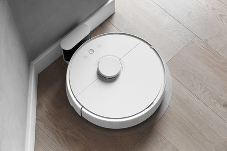White robot vacuum cleaner is charging on the docking station, smart cleaning, smart automatic vacuum cleaner is connected to the charging station in the interior.の写真素材