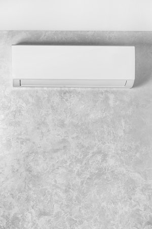 White air conditioner on a gray wall in a house, apartment. air conditioning system. The indoor unit of a split system for cooling and heating the room. Wall type air conditioner.の写真素材