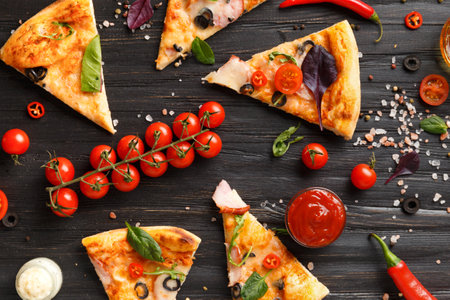 Pizza slices with jerky, olives, cheese and herbs are laid out on a dark wooden background, a branch of fresh cherry tomatoes, sauces and seasonings for pizza top view. Italian food.の写真素材