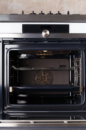 Built-in electric oven with an open door in the interior of the kitchen. Oven with display, convection. Built-in appliances for the kitchen.の写真素材