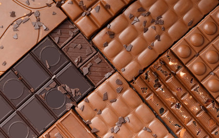 Whole chocolate, chocolate bars, candies, chocolate chips on a dark wooden background