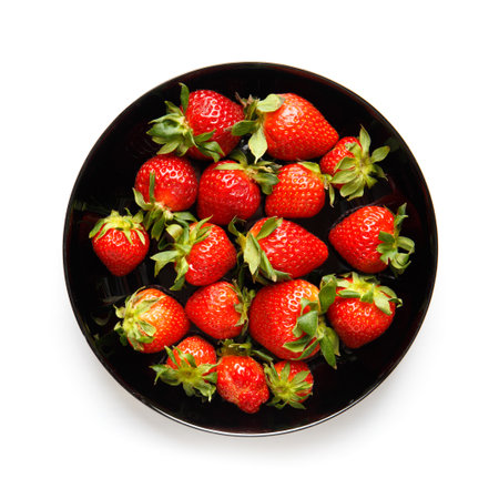 Large ripe juicy berries of organic strawberries in a black round plate isolated on a white background, top view.の写真素材