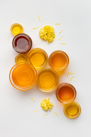 Honey in a glass bowls of different sizes on a white background top view. Creative composition of honey jars on isolation.の写真素材