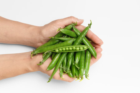 Pods of fresh green peas in hands on a white background, top view, close-up. Organic green peas in female palms. Vegetable protein, healthy products.の写真素材